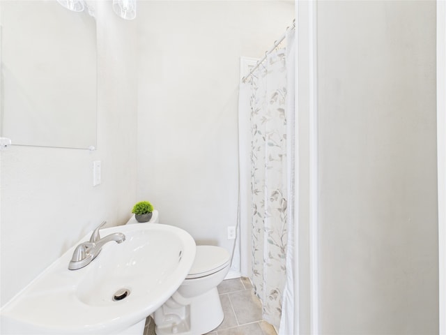 full bath featuring tile patterned flooring, curtained shower, toilet, and a sink