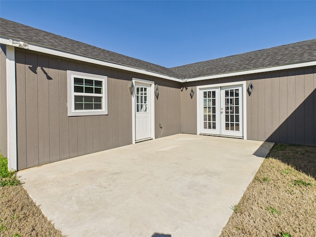 rear view of house featuring a patio area, french doors, and roof with shingles