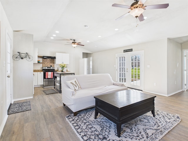 living area featuring french doors, baseboards, light wood-style flooring, and vaulted ceiling