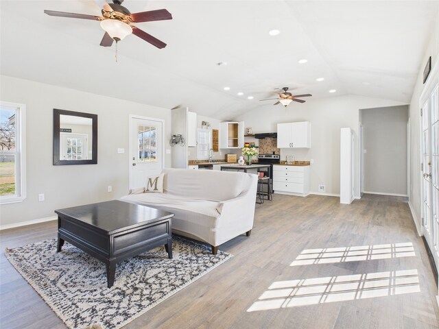 kitchen featuring white cabinets, electric range, vaulted ceiling, and sink