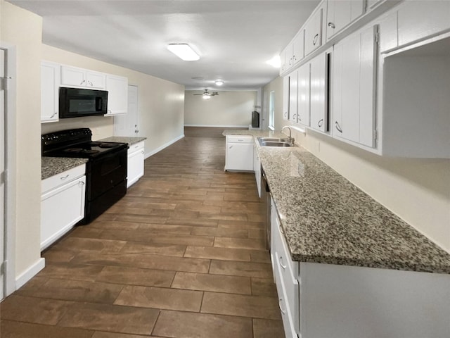 kitchen with sink, black appliances, dark stone countertops, kitchen peninsula, and white cabinets