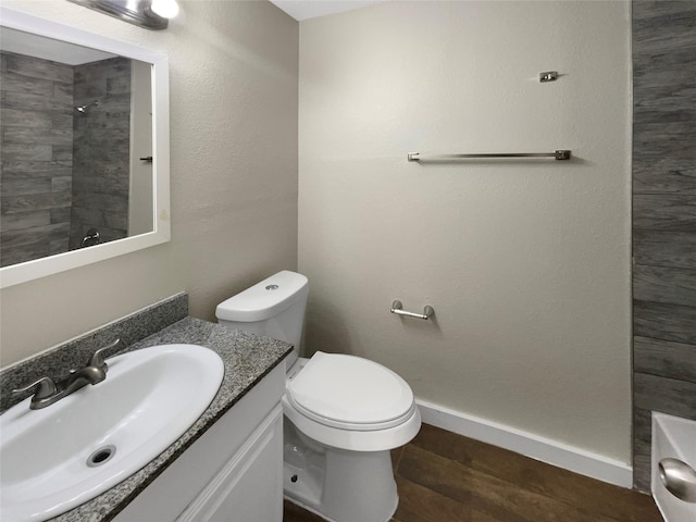 bathroom with tiled shower, wood-type flooring, toilet, and vanity