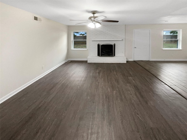 unfurnished living room featuring a fireplace, dark hardwood / wood-style floors, ceiling fan, and plenty of natural light