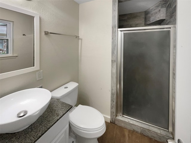 bathroom featuring vanity, hardwood / wood-style floors, a shower with door, and toilet