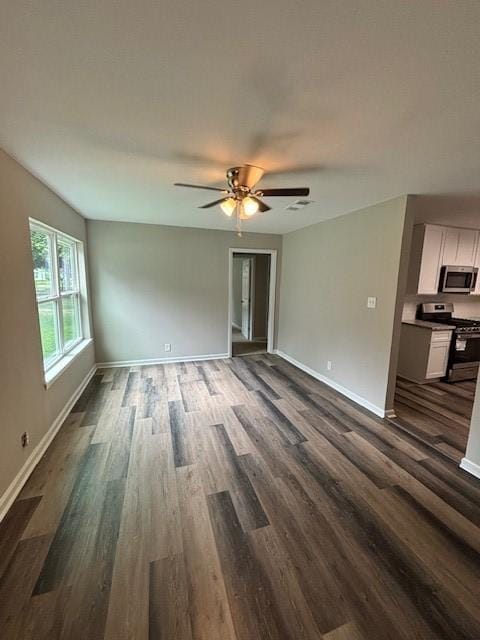 unfurnished living room featuring visible vents, dark wood finished floors, baseboards, and ceiling fan