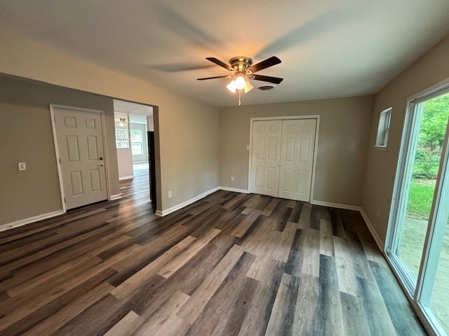 unfurnished bedroom with a closet, ceiling fan, access to exterior, and dark wood-type flooring