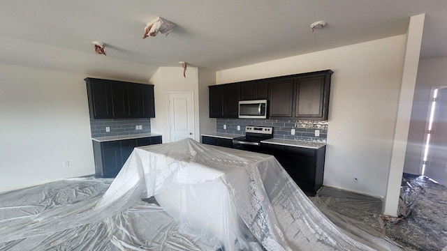 kitchen with appliances with stainless steel finishes, dark cabinets, marble finish floor, light countertops, and backsplash