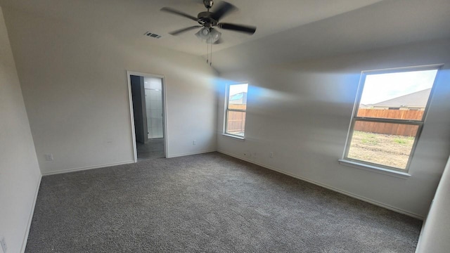 spare room featuring dark colored carpet and ceiling fan