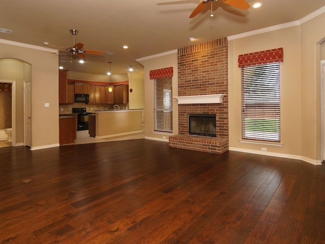 unfurnished living room featuring a fireplace, wood-type flooring, ornamental molding, and ceiling fan