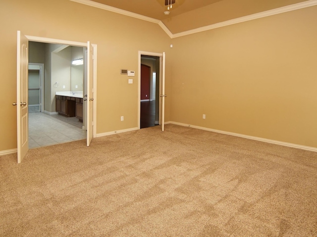 carpeted spare room featuring vaulted ceiling, ornamental molding, and ensuite bathroom