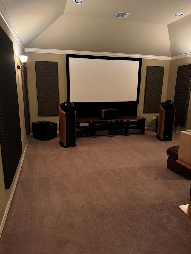 carpeted home theater with ornamental molding and vaulted ceiling