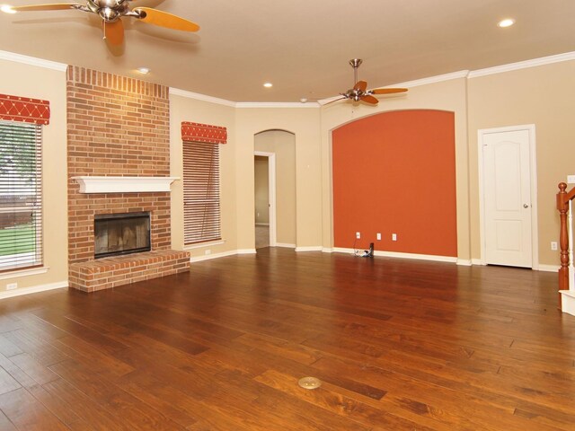 unfurnished living room with hardwood / wood-style floors, ceiling fan, brick wall, a fireplace, and ornamental molding