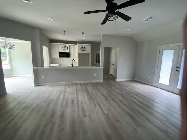 unfurnished living room with light hardwood / wood-style floors, sink, lofted ceiling, and ceiling fan