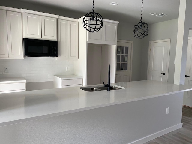 kitchen featuring sink, white cabinets, decorative light fixtures, and hardwood / wood-style flooring