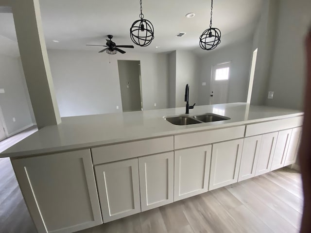 kitchen featuring white cabinets, a kitchen island, pendant lighting, and sink