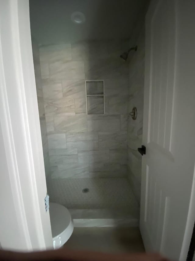 bathroom with toilet and a tile shower