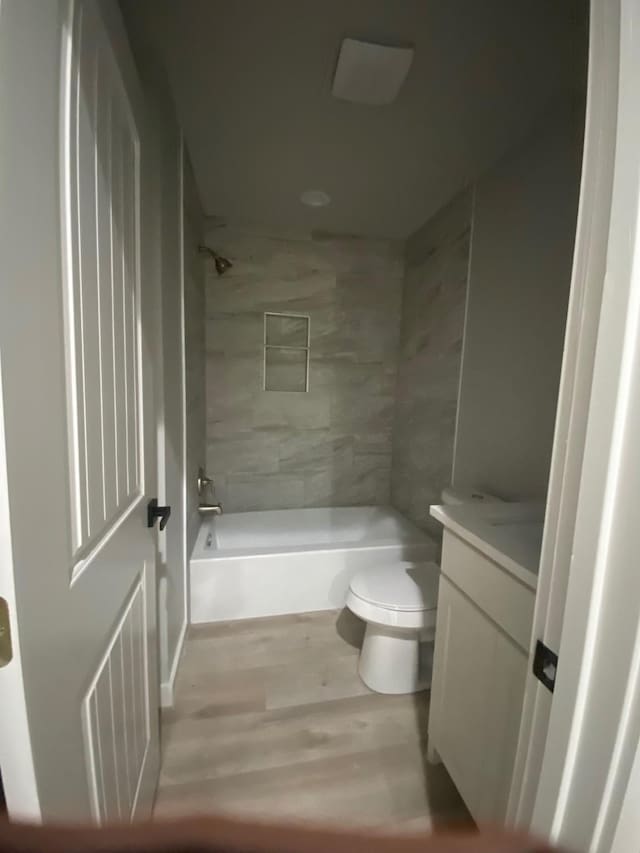 full bathroom featuring hardwood / wood-style flooring, toilet, vanity, and tiled shower / bath combo