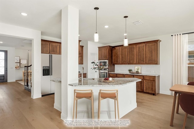 kitchen with white appliances, sink, light wood-type flooring, decorative light fixtures, and light stone counters