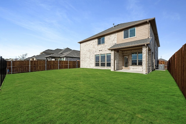 rear view of property featuring a lawn, central AC, and a patio area