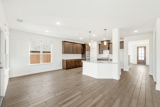 kitchen with backsplash, a wealth of natural light, stainless steel appliances, and decorative light fixtures