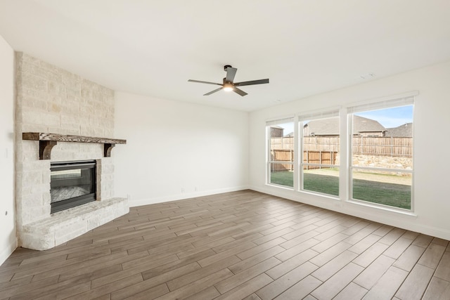 unfurnished living room with ceiling fan, a fireplace, and wood-type flooring