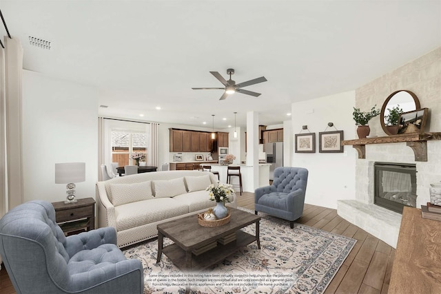 living room featuring ceiling fan and a stone fireplace