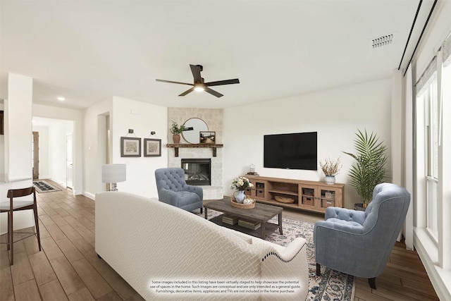 living room with a large fireplace, dark hardwood / wood-style floors, and ceiling fan