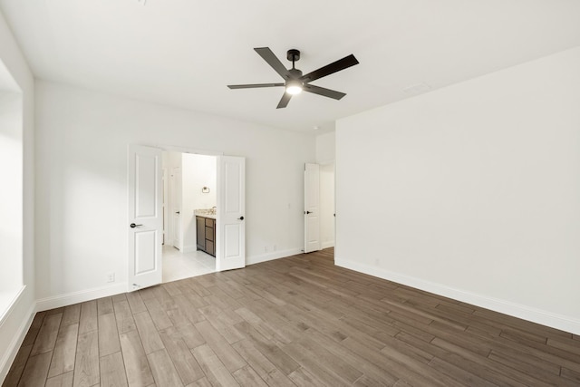 unfurnished bedroom featuring hardwood / wood-style flooring, ceiling fan, and connected bathroom