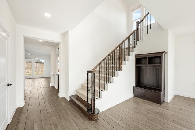 stairs featuring wood-type flooring, plenty of natural light, and ceiling fan