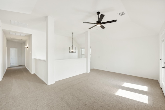 carpeted spare room with ceiling fan with notable chandelier and lofted ceiling