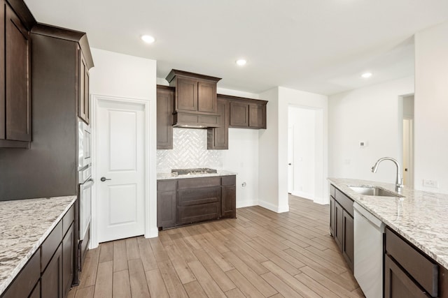 kitchen featuring light stone countertops, sink, light wood-type flooring, and appliances with stainless steel finishes