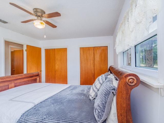 bedroom with multiple closets, a textured ceiling, and ceiling fan