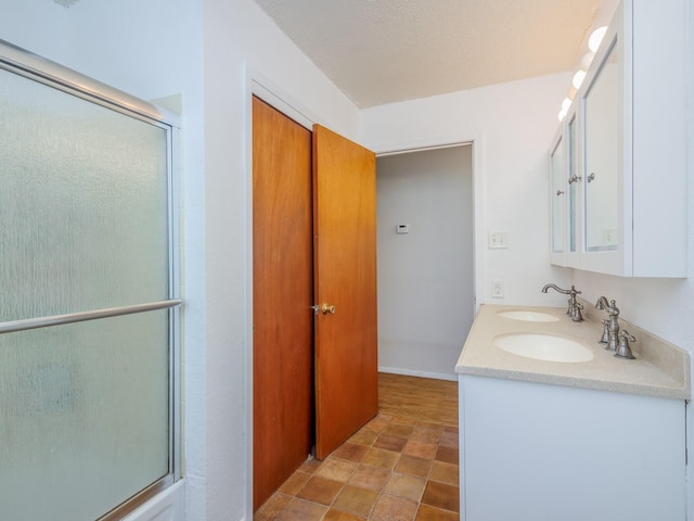 bathroom with a textured ceiling, a shower with shower door, and vanity