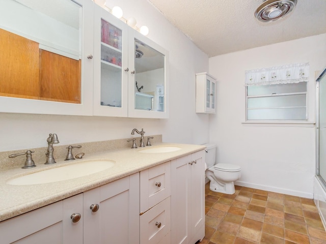 full bathroom featuring bath / shower combo with glass door, toilet, a textured ceiling, and vanity