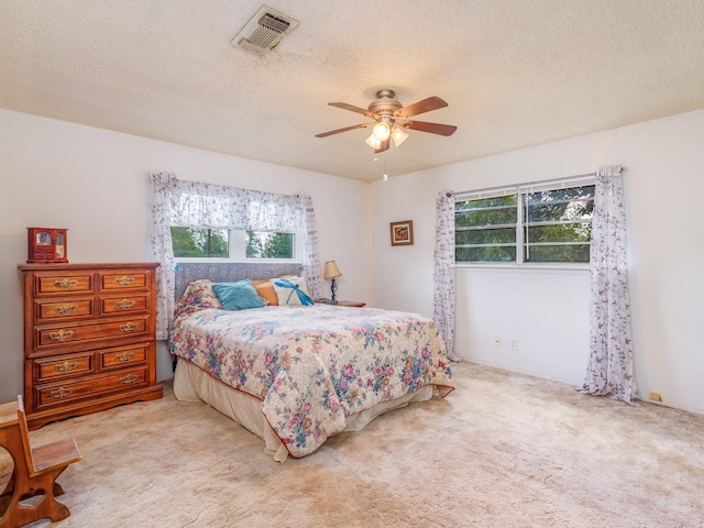 carpeted bedroom featuring ceiling fan, multiple windows, and a textured ceiling