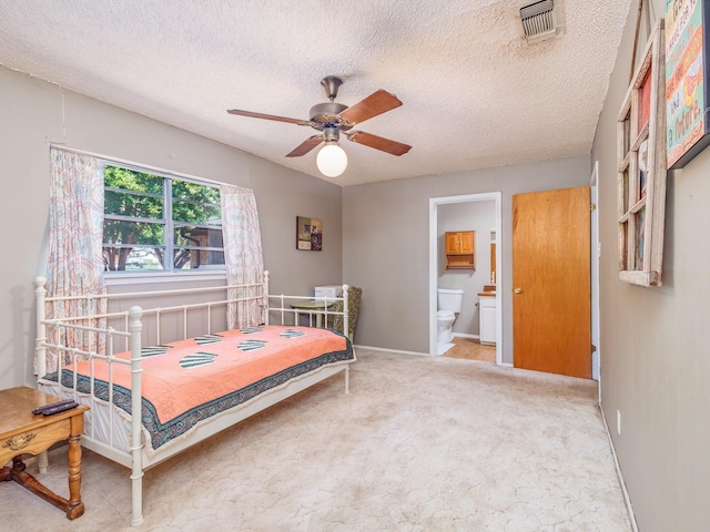 bedroom featuring ceiling fan, connected bathroom, a textured ceiling, and carpet flooring