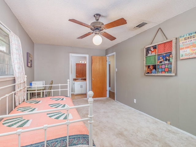 carpeted bedroom with sink, ceiling fan, ensuite bathroom, and a textured ceiling