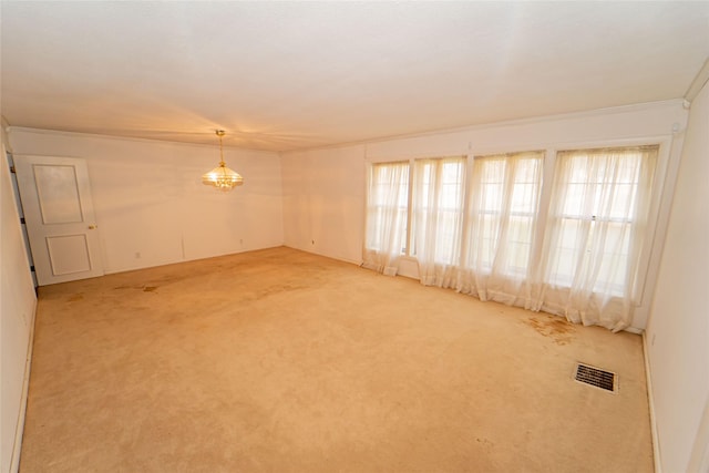 carpeted spare room with crown molding, plenty of natural light, and a notable chandelier