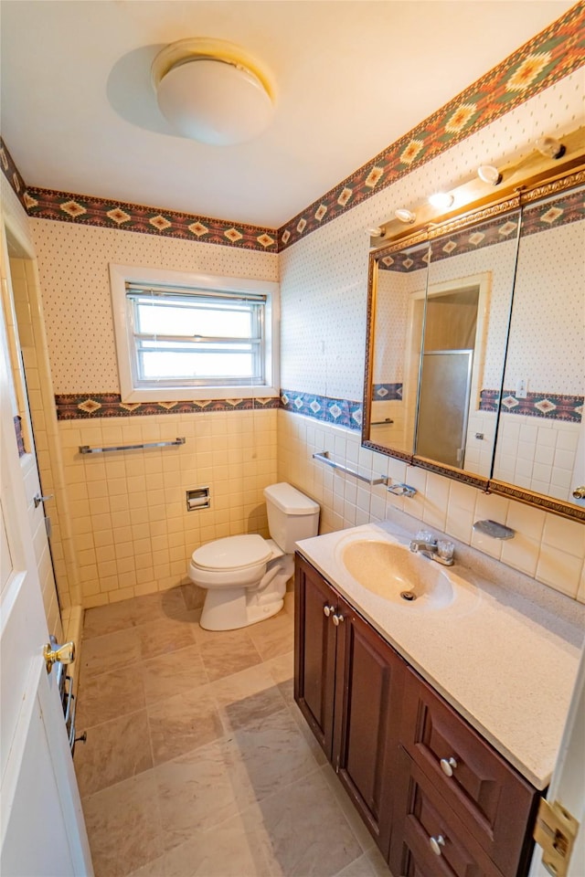 bathroom featuring vanity, toilet, an enclosed shower, and tile walls