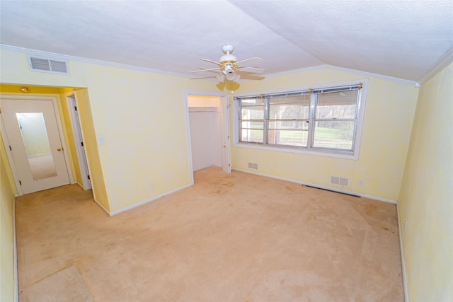 carpeted empty room featuring vaulted ceiling, ornamental molding, ceiling fan, and a textured ceiling