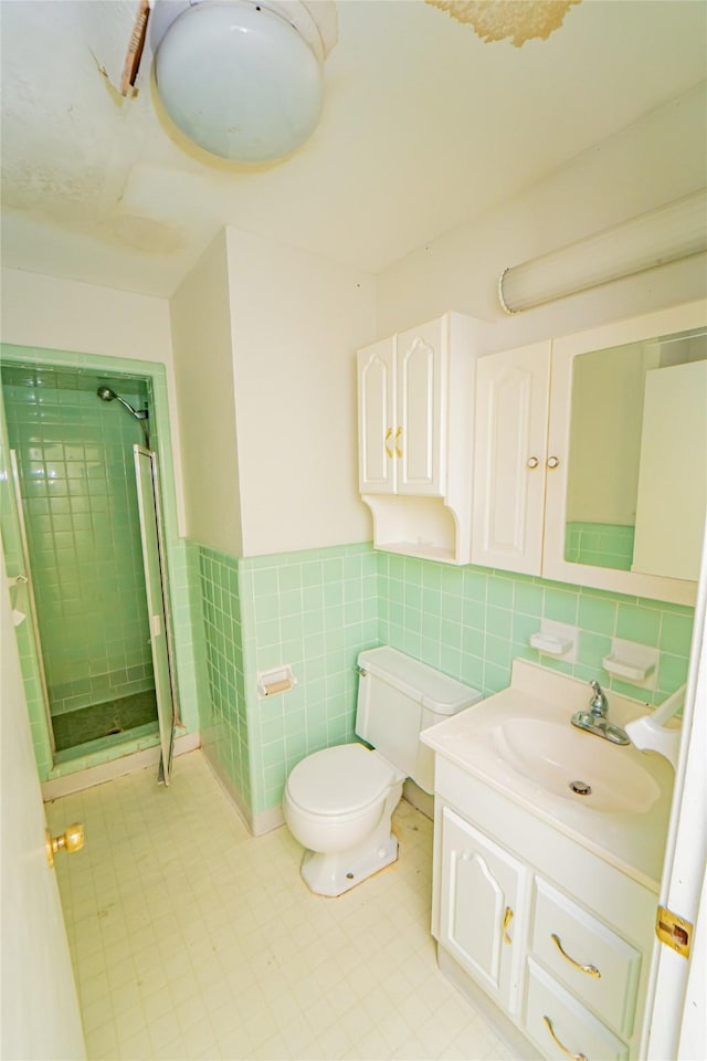 bathroom with tiled shower, vanity, toilet, and tile walls