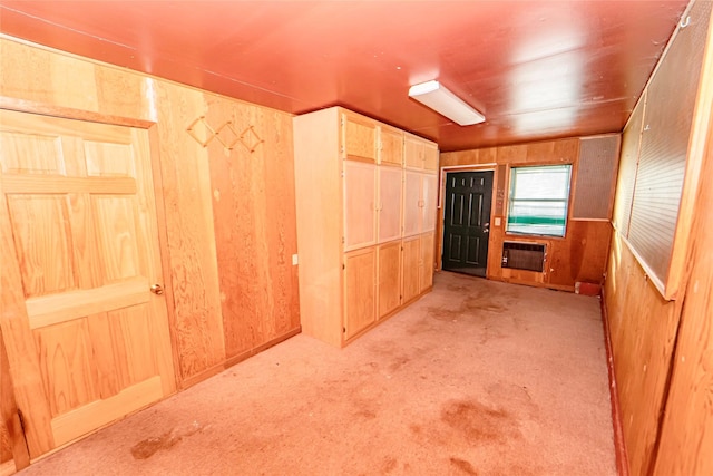 interior space with heating unit, light colored carpet, and wood walls