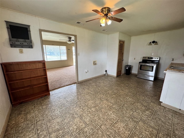 kitchen with stainless steel electric stove, wooden walls, and ceiling fan