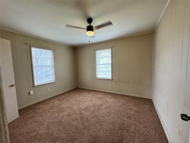 carpeted spare room featuring crown molding, a healthy amount of sunlight, and ceiling fan