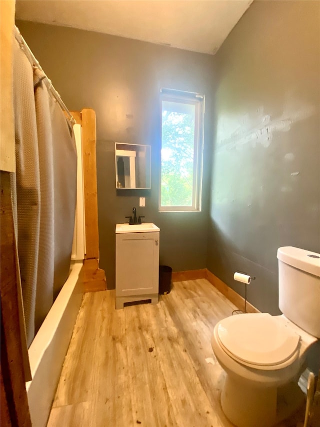 full bathroom with hardwood / wood-style floors, shower / tub combo, toilet, and vanity