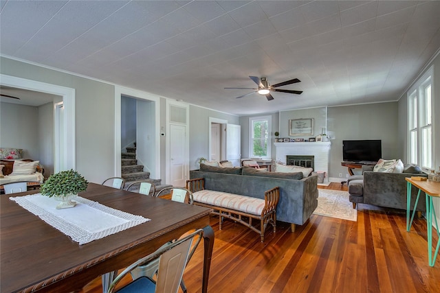 living room featuring hardwood / wood-style floors, a fireplace, ornamental molding, and ceiling fan