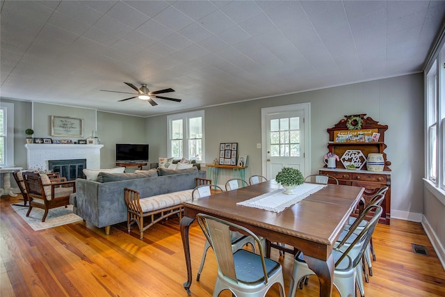 dining area with ornamental molding, a fireplace, and light hardwood / wood-style floors