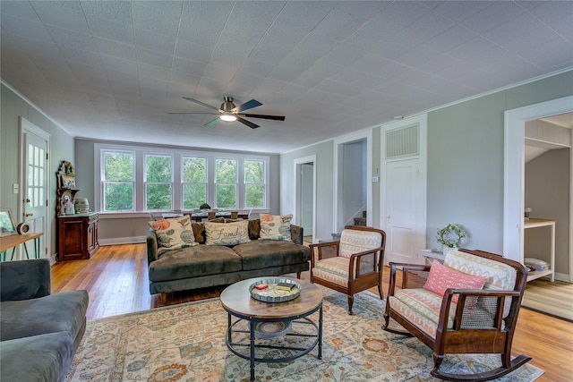 living room featuring ceiling fan, ornamental molding, and light hardwood / wood-style floors