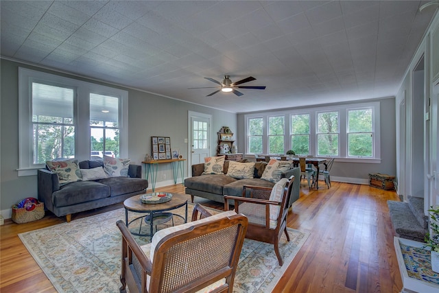 living room with crown molding, plenty of natural light, and light wood-type flooring