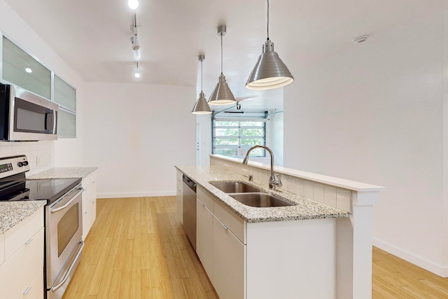 kitchen featuring backsplash, decorative light fixtures, appliances with stainless steel finishes, sink, and an island with sink